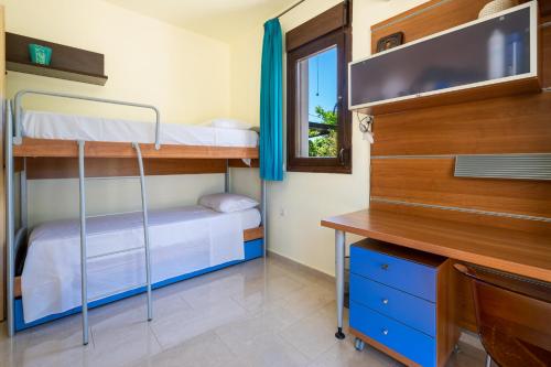 a bedroom with two bunk beds and a desk at Smaragdi Beachfront Villa in Asklipiḯon
