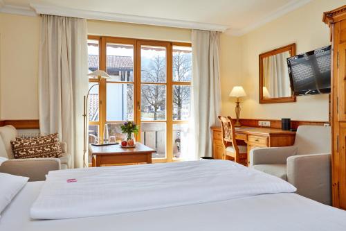 a bedroom with a bed and a desk and a television at Hotel Zugspitze in Garmisch-Partenkirchen