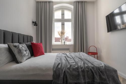 een slaapkamer met een bed met rode kussens en een raam bij HARBOR APARTMENTS - Mariacka in Katowice