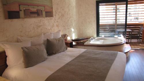 1 dormitorio con cama y bañera junto a una ventana en Ile du Gua Suites en Narbona
