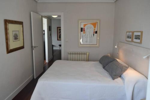 um quarto com uma grande cama branca num quarto em Apartamento cerca de la playa em Santander