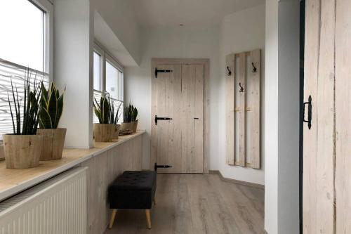 un pasillo con puerta, taburete y plantas en Ferienwohnung Birkenlodge en Schmallenberg