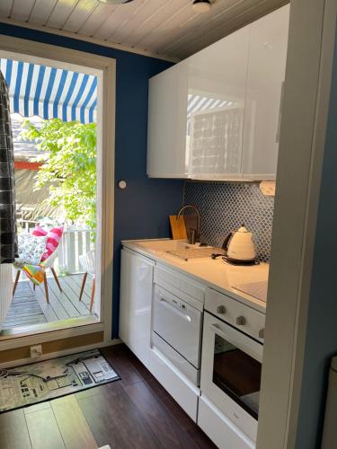 a kitchen with white cabinets and a door to a patio at Hotelli Kaivo in Naantali