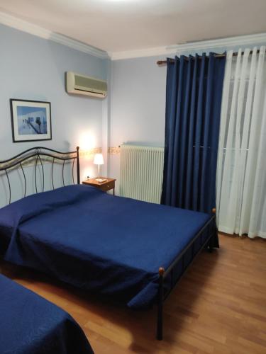 a bedroom with a blue bed and blue curtains at Vokamvilia Apartments in Kini