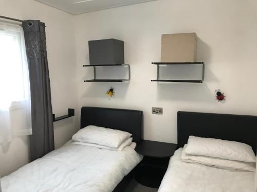 duas camas num quarto com prateleiras na parede em Bucklands - Chalet 15 em Westward Ho