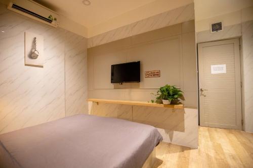 胡志明市的住宿－Lá Hotel Q10，一间卧室配有一张床和一台平面电视