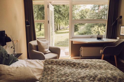 a bedroom with a bed and a window and a desk at Arnbjerg Pavillonen in Varde