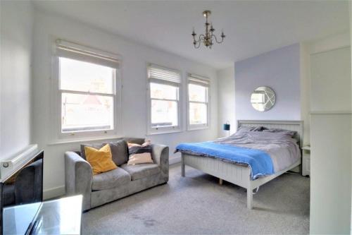 a bedroom with a bed and a couch and windows at Replingham Road Apartment in London
