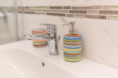 a bathroom sink with a striped soap dispenser on it at Balzano House in Scafati