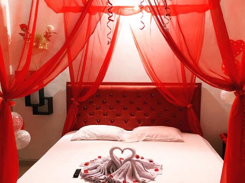 アパルタドにあるHotel San Miguel Apartadóのベッドルーム1室(赤いカーテン付きのベッド1台付)