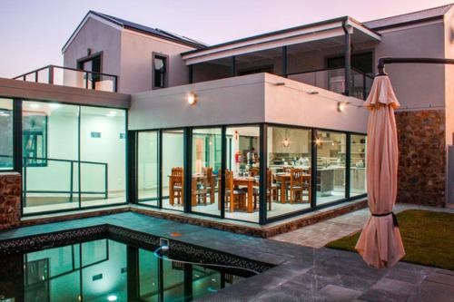 a large house with a swimming pool and an umbrella at Elizabeth House in Hermanus