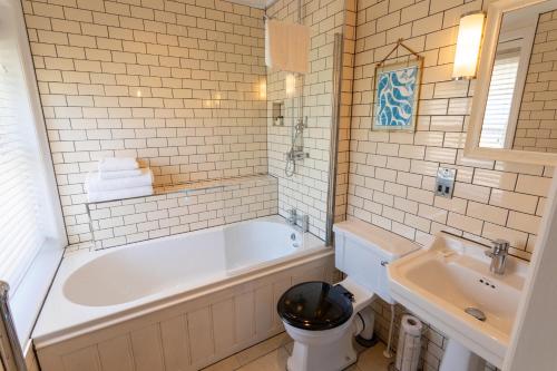 a white bathroom with a tub and a sink at The Smugglers Inn in Weymouth