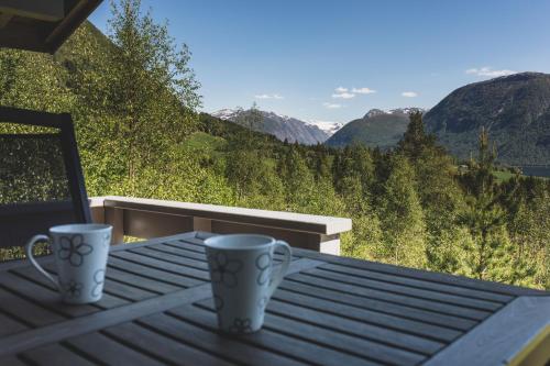 two coffee mugs sitting on a table with a view of mountains at Jølsterlia Hyttetun in Årdal