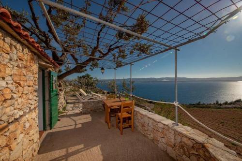 a table and chairs on a patio with a view of the water at Robinson Galisnjak with amazing SEA VIEW & JACUZZI in Bol