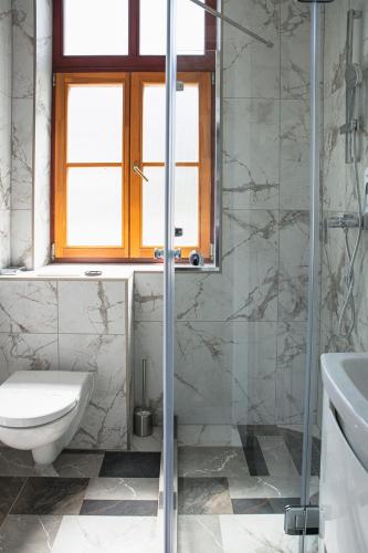 a bathroom with a toilet and a glass shower at Hotel Tókert Szálloda és Étterem in Lillafüred