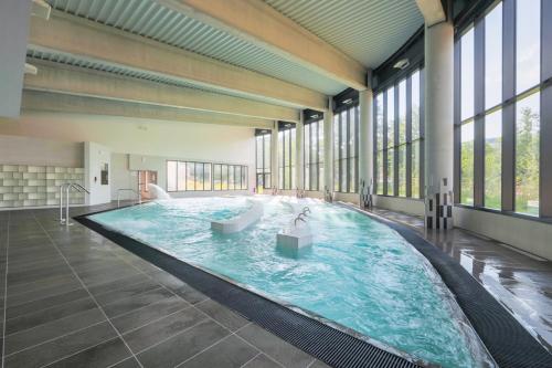 - une grande piscine dans un bâtiment doté de fenêtres dans l'établissement Villa Thermae Santenay, à Santenay