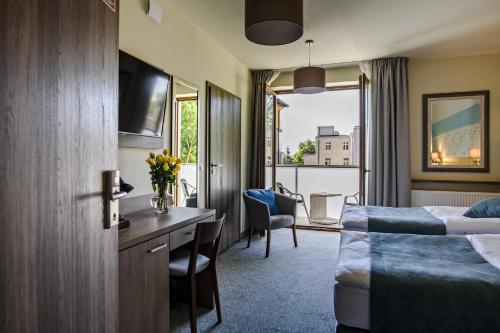 a hotel room with a bed and a desk at Hotel Brzozówka in Busko-Zdrój