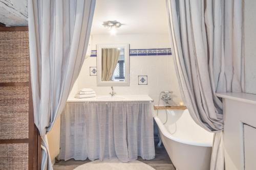 uma casa de banho com uma banheira e um lavatório e uma banheira em L'Auberge du Coignet em Dinan