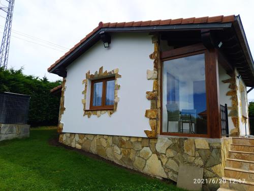 a small cottage with a stone wall and a window at La cabaña de Cortiguera in Cortiguera