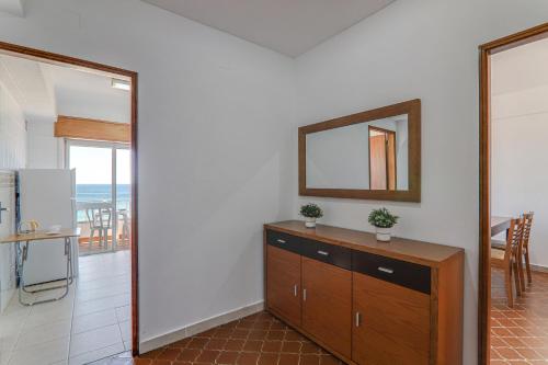 a room with a dresser and a mirror and a kitchen at Vista Mar 4ºc in Armação de Pêra