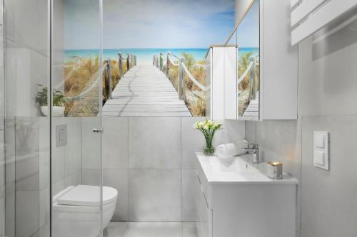 a bathroom with a toilet and a boardwalk to the beach at Elite Apartments Sopot Superior in Sopot