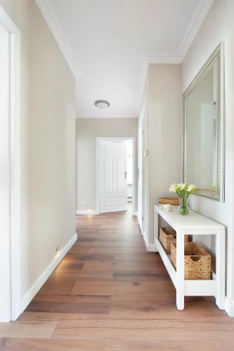 a hallway with white walls and a white table and mirror at Elite Apartments Sopot Superior in Sopot