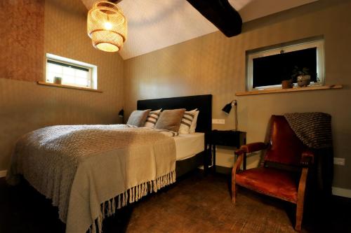 een slaapkamer met een bed, een stoel en een raam bij B&B Bergheide in Baexem