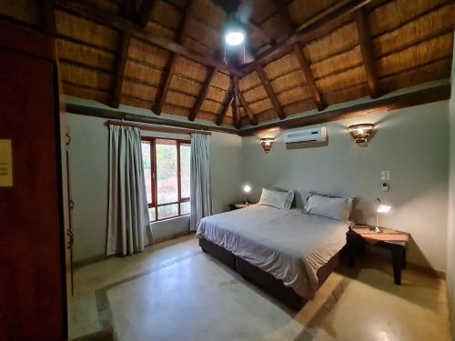 ein Schlafzimmer mit einem großen Bett in einem Zimmer mit Holzdecken in der Unterkunft Pumba's Place Zebula 6 Bedroom House in Mabula
