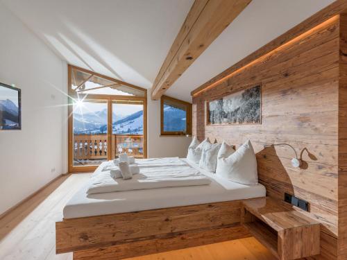 1 dormitorio con 1 cama grande y pared de madera en Chalet Weinberg Top 1 & Top 2 by Apartment Managers en Kirchberg in Tirol