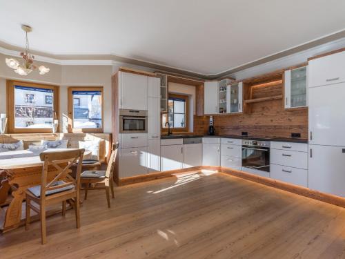 a kitchen with white cabinets and a table with chairs at Chalet Weinberg Top 1 & Top 2 by Apartment Managers in Kirchberg in Tirol