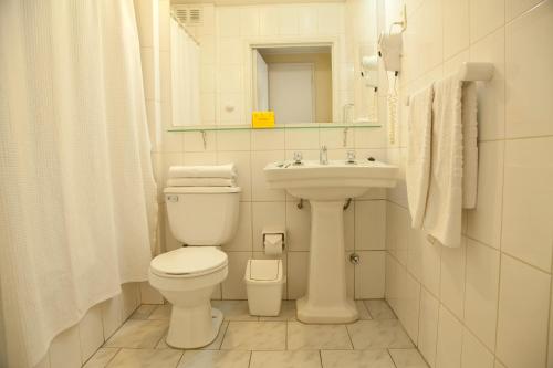 Baño blanco con aseo y lavamanos en Hotel Santa Lucia, en Santiago