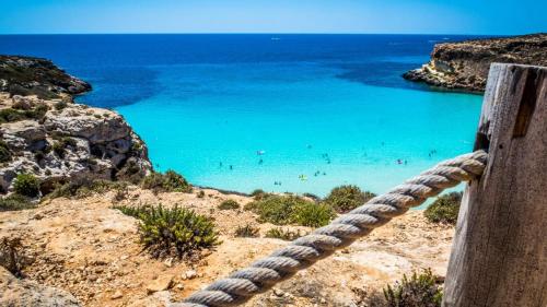 una cuerda que conduce a una playa con gente en el agua en Villa Zaffiro, en Lampedusa