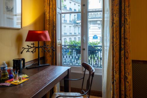 - un bureau avec une lampe et une chaise devant une fenêtre dans l'établissement Hôtel Relais Monceau, à Paris