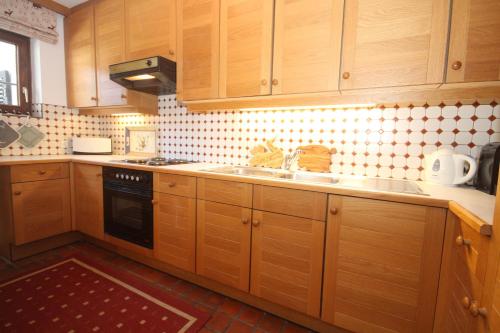 a kitchen with wooden cabinets and a sink at Apartment Kitzkamm by Apartment Managers in Kitzbühel