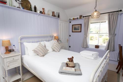 a bedroom with a white bed with a teddy bear sitting on it at The Smugglers Inn in Weymouth