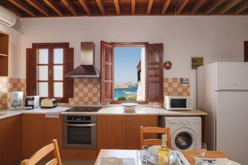 a kitchen with a window and a table with chairs at Thea Villas and Suite in Líndos