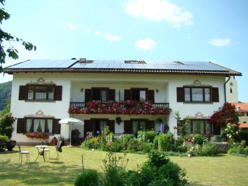 a large white house with a balcony with flowers at Gästehaus St. Bartholomä in Samerberg
