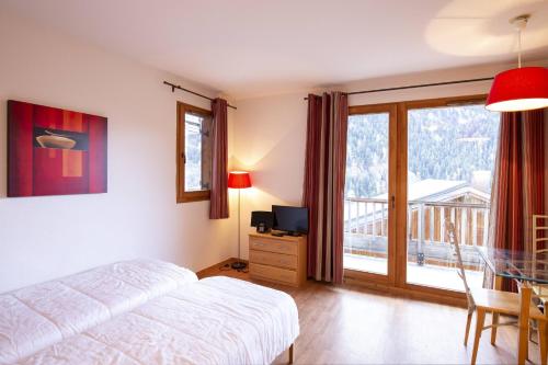 une chambre avec un lit et une télévision et un balcon dans l'établissement Le Hameau SPA & PISCINE studio 4pers by Alpvision Résidences, à Orelle