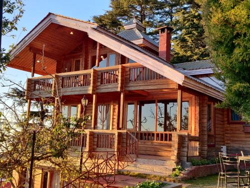 una casa de madera con un porche envolvente en The Chalets Naldehra, en Shimla