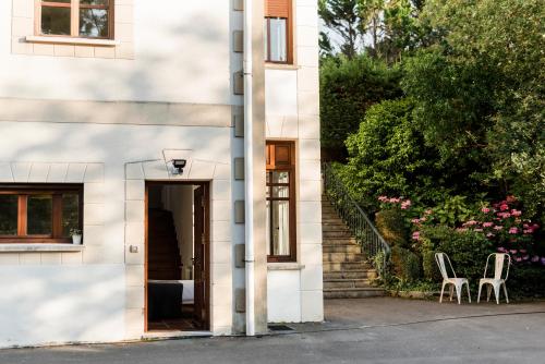 uma casa branca com duas cadeiras e escadas em Cozy Loft Barrika em Górliz-Elexalde