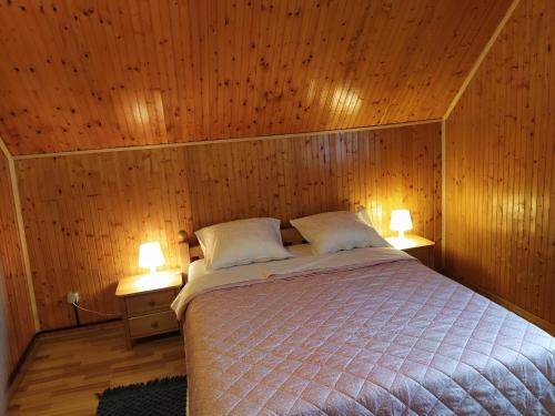 sypialnia z łóżkiem w drewnianej ścianie w obiekcie Apartmani San w mieście Jeziora Plitwickie