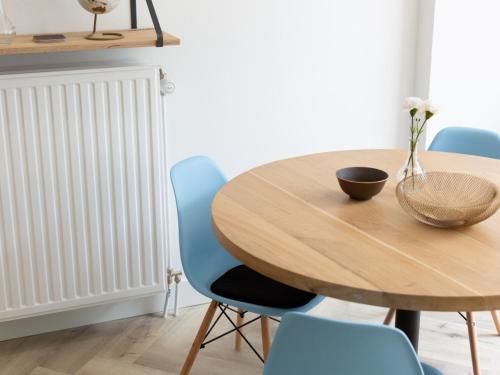 a dining room table with blue chairs and a wooden table at Hosted by Wendy Prins Willem 1 in Scheveningen