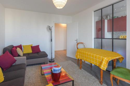 ein Wohnzimmer mit einem Sofa und einem Tisch in der Unterkunft Cozy and spacious with balcony and view over Seine in Clichy