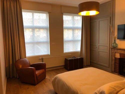 een slaapkamer met een bed en een stoel en 2 ramen bij Les chambres Berguoises Chambre Rez-de-chaussée au coeur de Bergues in Bergues