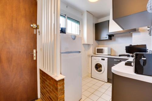 La cuisine est équipée d'un réfrigérateur blanc et d'un four micro-ondes. dans l'établissement Appartement Marinea - Welkeys, à Saint-Jean-de-Luz