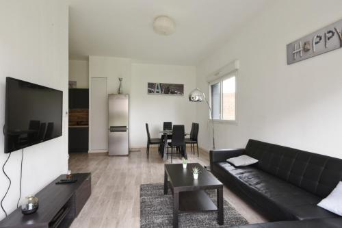 uma sala de estar com um sofá preto e uma mesa em Spacious 3-rooms with garden close to Lille em Lille