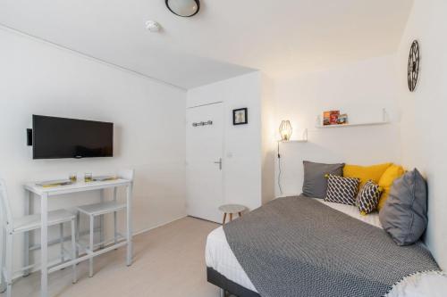 une chambre avec un lit et un bureau avec une télévision dans l'établissement Studio Payne - Welkeys, à Lyon