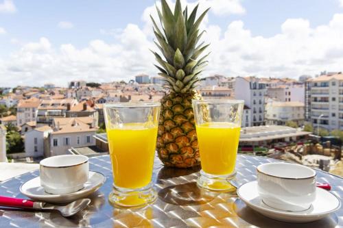 une table avec deux verres de jus d'orange et un ananas dans l'établissement Studio Thalmar - Welkeys, à Biarritz
