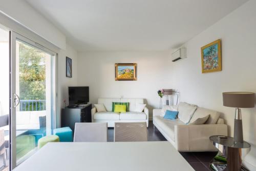 a living room with white furniture and a large window at Appartement Oasis - Welkeys in Antibes