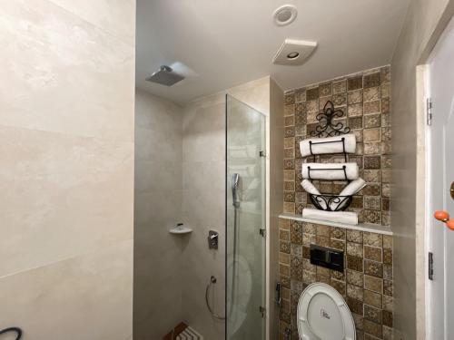 a bathroom with a shower and a toilet and towels at Marbella Dehradun in Dehradun